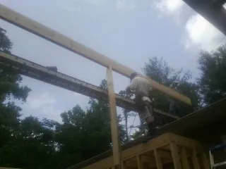 Carpenter setting a ridge beam over a new addition frame — Ice Dam Removal by Roofing Brothers in Madera