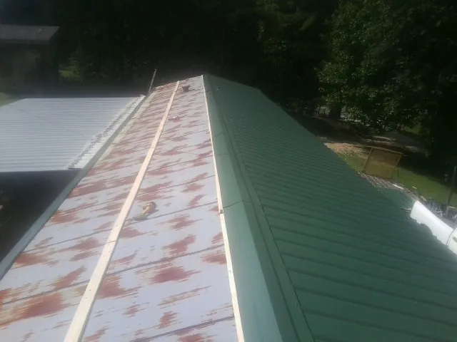 Old rusted panels beside newly installed green metal roofing — Wind Damage Roof Repair by Roofing Brothers in Madera