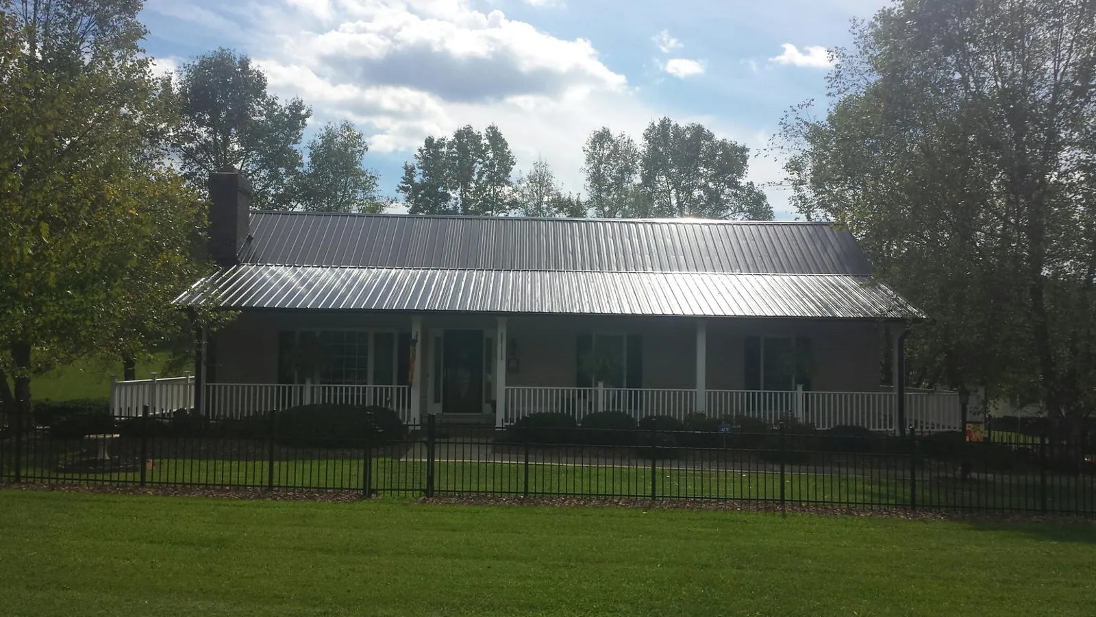 Gray metal roof on a brick ranch with a full width front porch — Gutter Guard Installation work by our crew in Madera