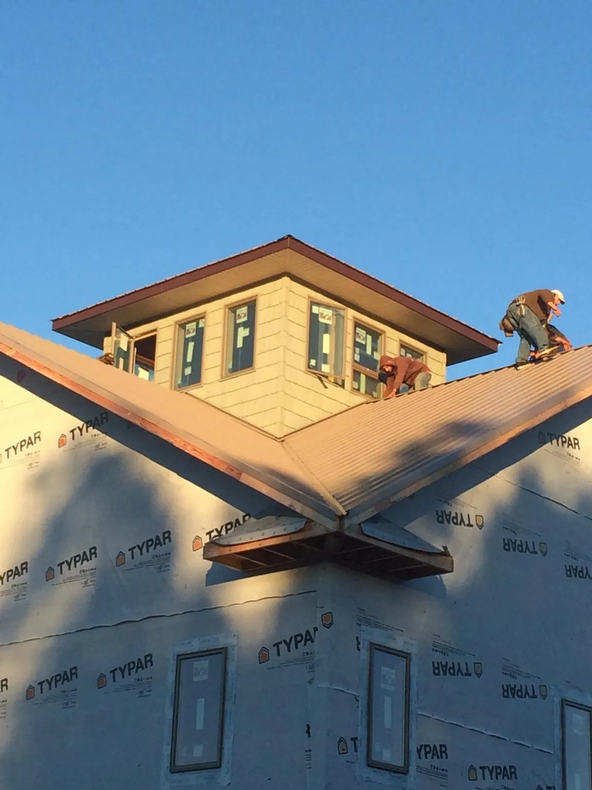 Roofers working around a rooftop cupola on a new metal roof at sunset — Roof Waterproofing in Madera by Roofing Brothers